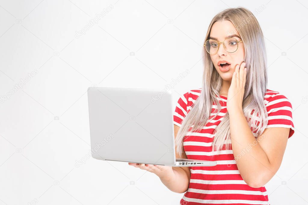Wow! It's amazing! Portrait of happy young beautiful surprised woman standing with laptop isolated on white background. Space for text.