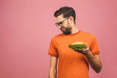 Sağlıksız hamburgeri reddeden yakışıklı genç adam pembe arka planda izole edilmiş. Diyet konsepti. Metin için kopyalama alanı ile.