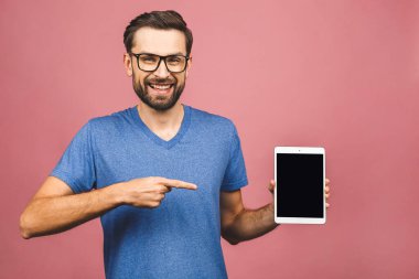 Ürün sunumu. Terfi ettim. Genç adam elinde boş ekranla tablet bilgisayarını tutuyor, kapat. Pembe arka planda izole edilmiş. 