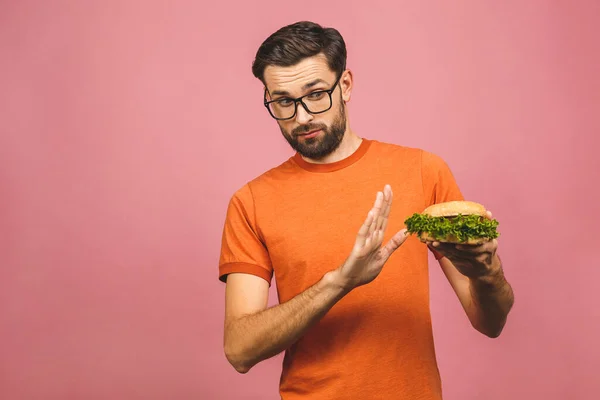 英俊的年轻人拒绝不健康的汉堡包 被粉色背景隔离了 节食的概念 带有文本复制空间 — 图库照片