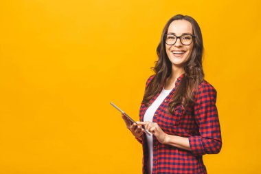 Fotokopi alanı boş, oldukça çekici, kendine güveni olan, tabletli bir kadının sarı arka planda izole edilmiş portresi..