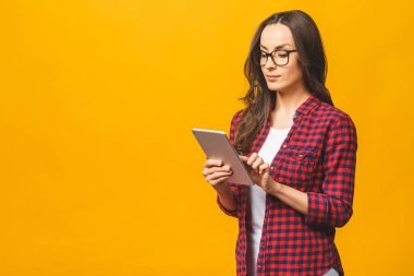 Fotokopi alanı boş, sevimli, kendine güveni tam bir kadının tabletinin sarı arka planda izole bir şekilde duran portresi..