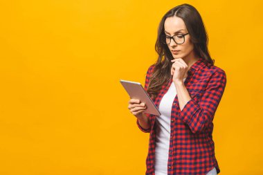 Fotokopi alanı boş, sevimli, kendine güveni tam bir kadının tabletinin sarı arka planda izole bir şekilde duran portresi..