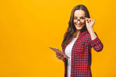 Fotokopi alanı boş, sevimli, kendine güveni tam bir kadının tabletinin sarı arka planda izole bir şekilde duran portresi..