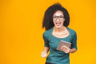 Mutlu Afrikalı Amerikalı kız heyecanla tablet ekranına bakıyor zaferi kutluyor çığlıklar atıyor ve gülüyor. Başarı, mutluluk, neşe konsepti.