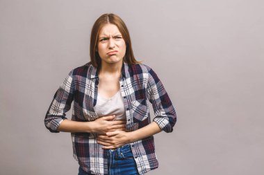 Gri arka planda karın ağrısı olan güzel bir kadın..