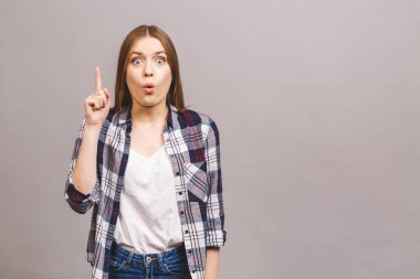 Gri arkaplanda izole bir şekilde kameraya bakarak, gündelik bir şekilde genç bir kadının yakın plan portresi..