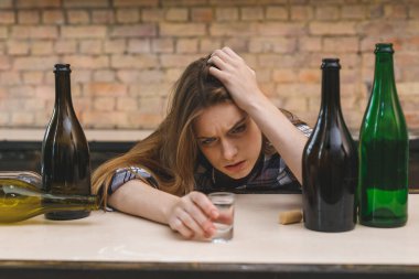 Genç kadın alkolik sosyal sorunlar kavramı mutfakta gözleri kapalı oturuyor. Depresyonda olan genç bir kız çocuğu acı çekerek ve ağlayarak kötü muamele görüyor.. 