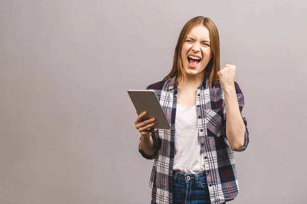 Happy winner woman excited holding tablet pc isolated on grey background. Cheerful happy fresh Caucasian female model.