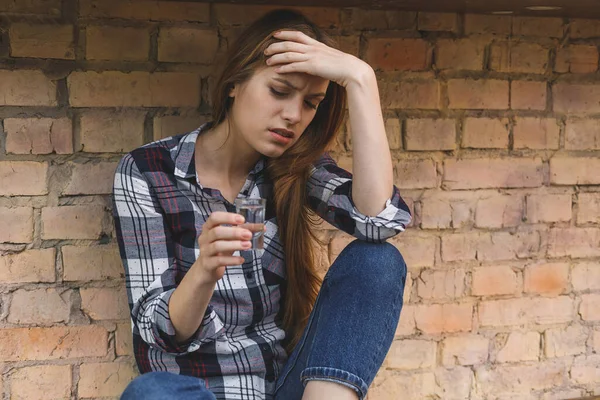 Young woman alcoholic social problems concept sitting with closed eyes in kitchen. Depression young female teenager having abused problem feeling suffering and crying.