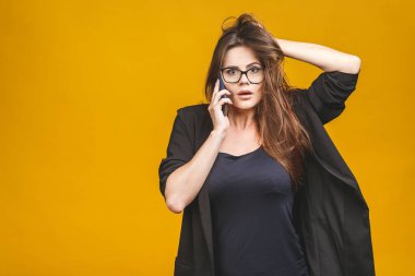 Sarı arka planda telefonla konuşan akıllı, şaşkın bir kadının portresi..