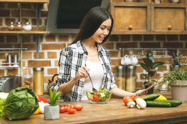 Mutfakta tablet bilgisayarlı genç ve güzel bir kadın yemek tarifleri buluyor. Gıda blogcusu kavramı