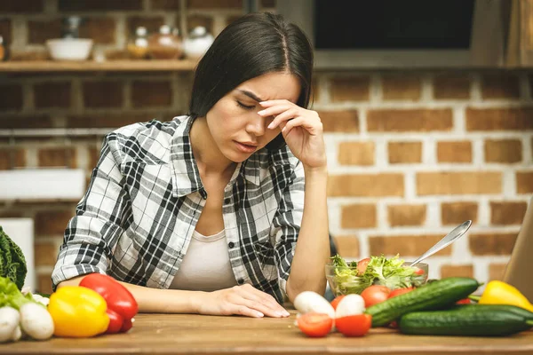 Stressed beautiful young woman in kitchen. Tired at home. Food concept.