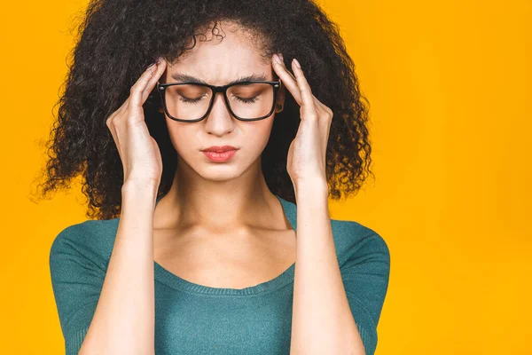 Nervous african woman breathing calming down relieving headache or managing stress, black girl feeling stressed massaging temples exhaling isolated on yellow background.