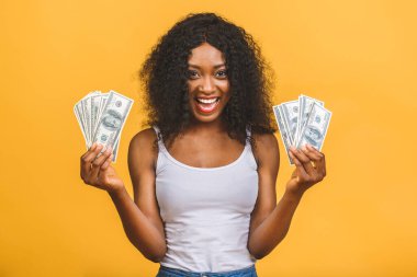 Mutlu galip. Afro saçlı, 20 'li yaşlarda Amerikalı başarılı bir kadının portresi. Sarı arka planda izole edilmiş bir sürü para banknotları var..