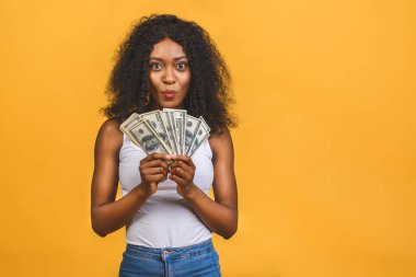 Mutlu galip. Afro saçlı, 20 'li yaşlarda Amerikalı başarılı bir kadının portresi. Sarı arka planda izole edilmiş bir sürü para banknotları var..