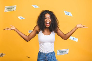 Sarı arka planda izole edilmiş parayla yağmurun altında duran neşeli Afro-Amerikan bir kadının konsept fotoğrafı..