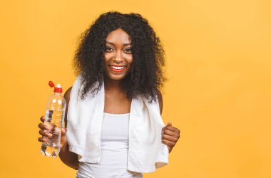 Egzersiz sonrası su içen, susuzluğunu gideren, sarı arka planda izole edilmiş, güzel, çekici, genç, terli, Afro-Amerikan siyahi kadın..