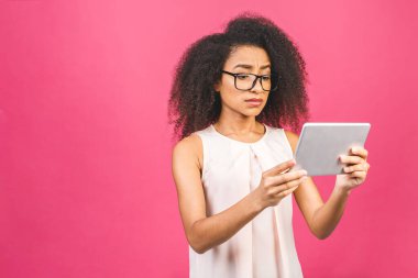 Kıvırcık saçlı, elinde dijital tablet bulunan, izole edilmiş pembe arka planı olan, metin, logo ya da reklam için fotokopi alanı olan yalnız ve üzgün Amerikalı genç bir kız öğrenci..