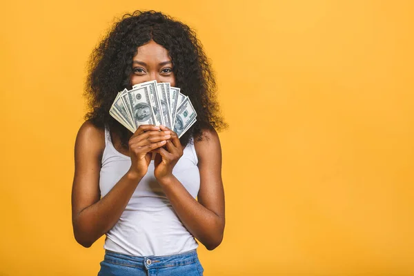 Mutlu galip. Afro saçlı, 20 'li yaşlarda Amerikalı başarılı bir kadının portresi. Sarı arka planda izole edilmiş bir sürü para banknotları var..