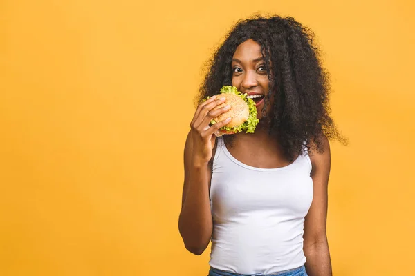 Αφρικανική Αμερικανική Μαύρη Όμορφη Νεαρή Γυναίκα Τρώει Χάμπουργκερ Απομονωμένη Κίτρινο — Φωτογραφία Αρχείου