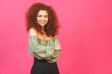 Pembe arka planda kollarını kavuşturmuş gülümseyen genç bir kadının portresi.. 