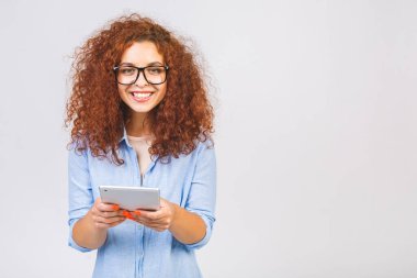 Beyaz arka planda izole edilmiş tablet kullanarak gülümseyen güzel kıvırcık kız. Boşluğu kopyala.