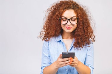 Beyaz arka planda izole bir şekilde cep telefonuyla sohbet eden neşeli, tatlı, kıvırcık, güzel bir genç kadının fotoğrafı.. 