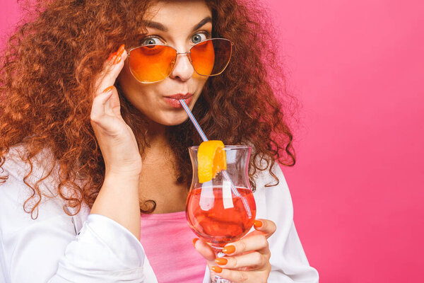 Счастливая красивая женщина в летней повседневной одежде с бокалом коктейльного напитка студии выстрел изолирован на красочный розовый backgroud.
