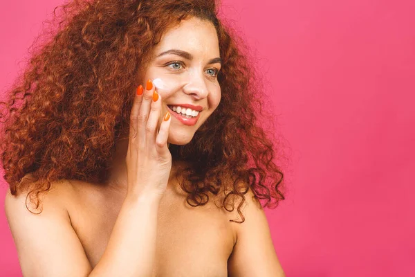 Yüzüne krem sürerken gülümseyen güzel bir kadının portresi..