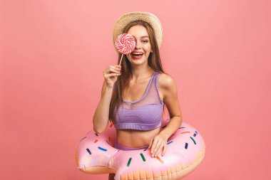 Mayo giymiş mutlu genç bir kadının portresi. Elinde pembe arka planda izole edilmiş yüzülebilir bir yüzük var. Şeker tutarken.