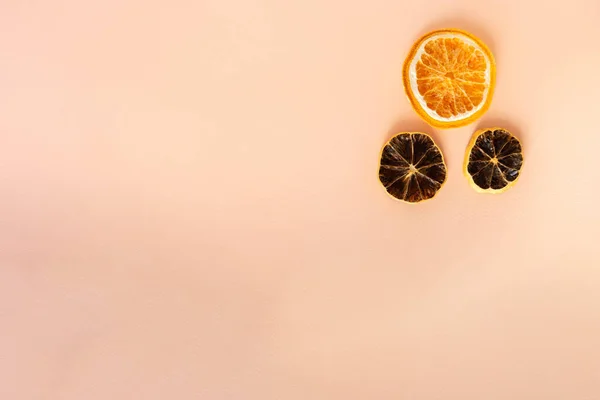 Düz kompozisyonda üç dilim turuncu ve kahverengi-kırmızı portakal vardı. Meyve dilimleri sağ üst köşede bulunur. Açık pembe arkaplanda kağıt desenli nesneler. Üst