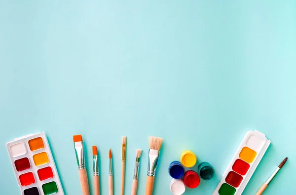 Yatay yakın çekim düz kompozisyon, turuncu ve ahşap desenli üç açık bej fırça, beyaz kazıklı üç fırça, kahverengi kazıklı bir fırça, iki set suluboya.