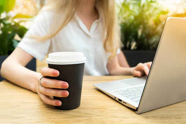 Masada oturan çizgili ceketli beyaz iş kadını tarafından kullanılan defterin yakın fotoğrafını çek. Yakınlarda plastik bir fincan kahve var. İş kadını konsepti. Yaşam tarzı kavramı.
