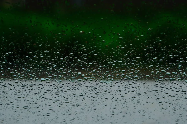 Rain drops after the cloudburst on the window. Green background.