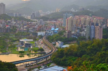 S biçimli otoban, şehrin içinden geçerek Alacakaranlık Altındaki göl ve dağların yanından geçer.