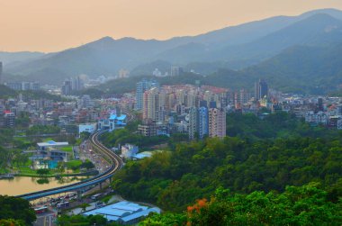 S biçimli otoban, şehrin içinden geçerek Alacakaranlık Altındaki göl ve dağların yanından geçer.
