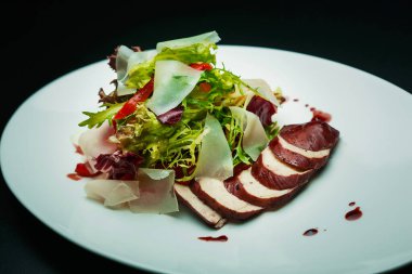 Sezar salatası ve tavuk göğsü. Beyaz tabakta kırmızı şarap.