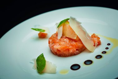 Deniz tarağı somonu, peynir ve fesleğen yaprakları beyaz tabakta.