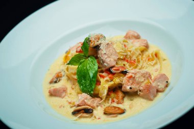 Beyaz tabakta fesleğen yapraklı deniz ürünleri tagliatelle.