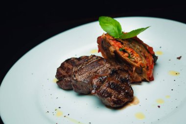 Beyaz tabakta lazanya olan dana madalyonları.