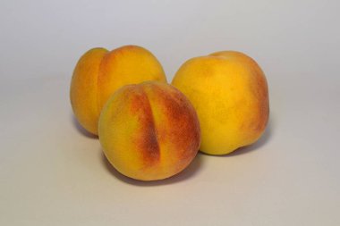 Beyaz arka planda üç olgun şeftali..