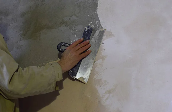 Male hand with a trowel. The process of plaster walls.