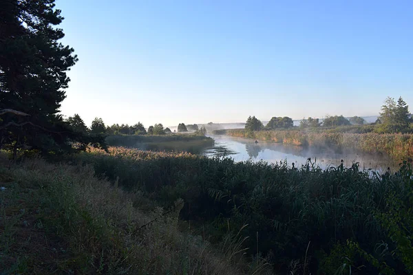 Landscape: river with morning fog and beautiful sunlight, boat on the river.