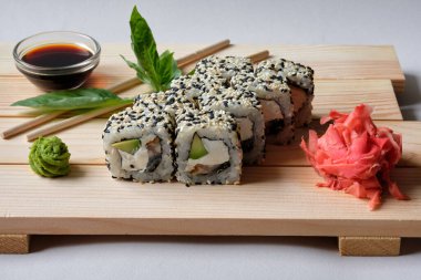Wasabi, soya sosu, fesleğen yaprağı ve terbiye edilmiş zencefilli Japon suşisi. Restoran veya kafe menüsü için lezzetli ve sanatsal yemekler. Tahtada yuvarlan..