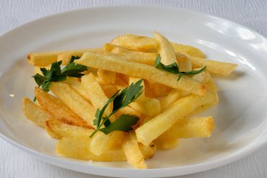 Beyaz tabakta maydanozlu kızarmış patates. Kataloğuma tam menü yükle. Yemek fotoğrafçılığı. 