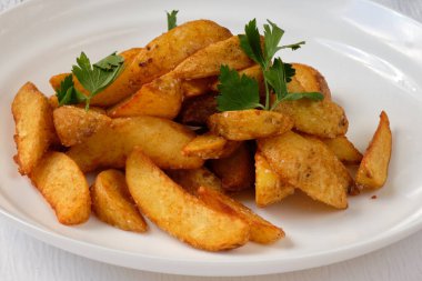 Beyaz tabakta maydanozlu kızarmış patates. Kataloğuma tam menü yükle. Yemek fotoğrafçılığı. 