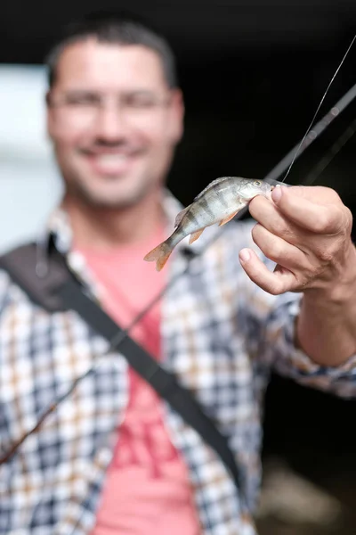 the fisherman is happy that a fish is caught on his spinning rod. Man shows fishing skills. Concept of hobby and fishing sport. Small depth of field.
