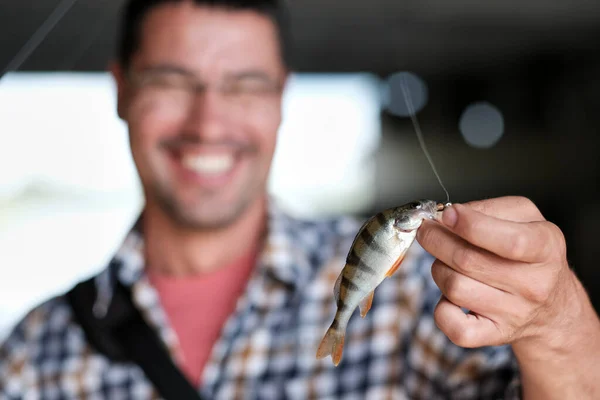 the fisherman is happy that a fish is caught on his spinning rod. Man shows fishing skills. Concept of hobby and fishing sport. Small depth of field.