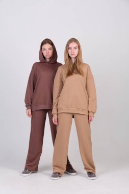 Giysi kataloğu için stüdyoda kahverengi ve bej renkli günlük kıyafetlerle poz veren bir çift modaya uygun model. Sonbahar kadın modasının örnekleri. Boşluğu kopyala.